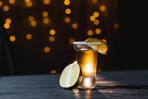 Mexikaner Gold Tequila mit Limette und Salz- auf schwarz Hintergrund mit Exemplar. foto