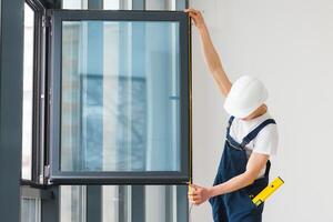 Arbeiter im Overall Installation oder einstellen Plastik Fenster im das Leben Zimmer beim Zuhause foto