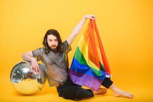 Fröhlich Mann halt Regenbogen gestreift Flagge isoliert auf farbig Hintergrund Studio Porträt. Menschen Lebensstil Mode lgbtq Konzept foto