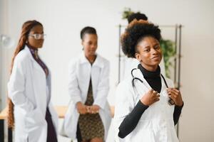 Porträt von ein lächelnd Krankenschwester im Vorderseite von ihr medizinisch Team. foto