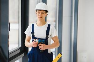 Arbeiter im Overall Installation oder einstellen Plastik Fenster im das Leben Zimmer beim Zuhause foto