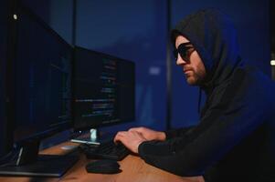 Hacker Sitzung beim Schreibtisch im dunkel Atmosphäre. ein Computer Programmierer oder Hacker. anonym Computer Hacker. foto