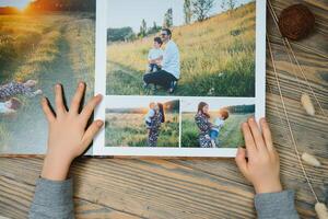 das Hand Kind halten ein Familie Foto Album gegen das Hintergrund von das ein hölzern Tabelle