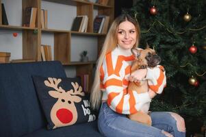 schön Mädchen Sitzung auf das Couch mit ein Hund auf das Hintergrund von Weihnachten foto