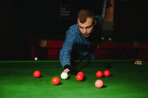 jung gut aussehend Mann gelehnt Über das Tabelle während spielen Snooker foto