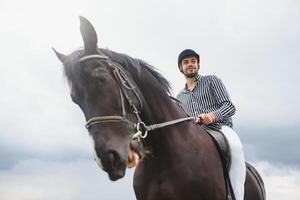 schön Mann Reiten ein Pferd auf Feld beim Sommer- foto