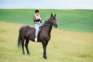 jung Frau Reiten ein Pferd auf das Grün Feld foto