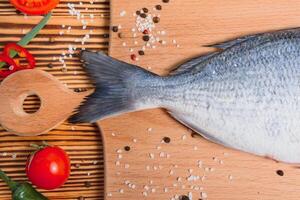 roh Fisch Kochen und Zutaten. Dorado, Zitrone, Kräuter und Gewürze. oben Aussicht mit Kopieren Raum auf Tabelle foto