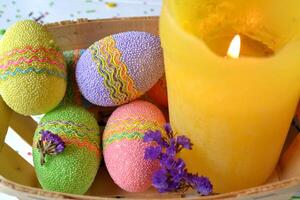 bunt Ostern Eier mit Blumen und Gelb Kerze im das Korb. schön Ostern Hintergrund. Ostern Karte. hausgemacht Urlaub Dekor. foto