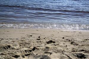 nass Sand und Sanft Wellen auf ein Strand. foto