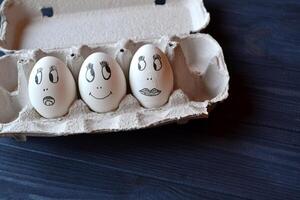 Eier mit ein Gesichter im ein Container Box auf das hölzern Tisch. kreativ Ostern Hintergrund. glücklich Ostern Tag. foto