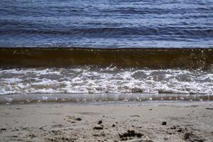 nass Sand und Sanft Wellen auf ein Strand. foto