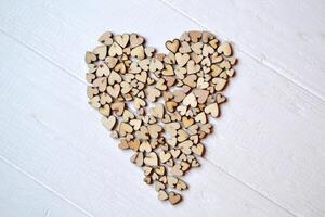 dekorativ hölzern Herzen im ein bilden von Herz auf ein Weiß Schreibtisch. Liebe Hintergrund. foto