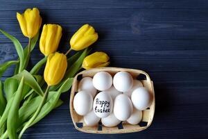 Gelb Tulpen und Eier auf ein Blau hölzern Hintergrund. glücklich Ostern. foto