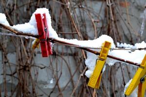 Kleider Heringe bedeckt durch Schnee auf das Seil draussen. foto