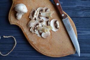 Pilze auf das dunkel Blau hölzern Schreibtisch. Kochen Champignons. foto