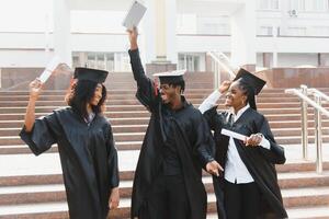 Ausbildung, Abschluss und Menschen Konzept - - Gruppe von glücklich International Studenten im Granatwerfer Bretter und Junggeselle Kleider mit Diplome foto