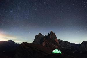 herausragender Ort. Nachtfoto von Seceda Dolomiten. Touristen, die sich im grünen Zelt ausruhen