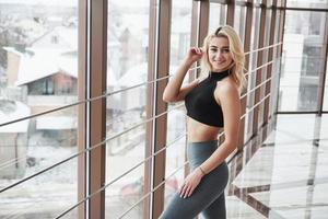 Winter draußen. wunderschönes blondes Mädchen in Sportkleidung posiert im Fitnessstudio in der Nähe des Fensters