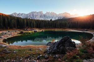 Sonnenstrahl über den Bäumen. Herbstlandschaft mit klarem See, Tannenwald und majestätischen Bergen foto