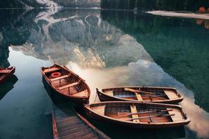 komm einfach rein und schwimm. Holzboote auf dem Kristallsee mit majestätischem Berg dahinter. Spiegelung im Wasser foto