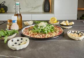 Mund Bewässerung Carpaccio gemacht mit frisch, hohe Qualität Zutaten gelegt aus auf ein glatt schwarz Marmor Arbeitsplatte foto