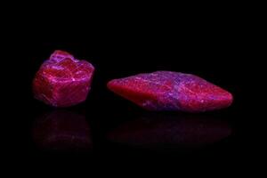 Makro Mineral Stein Rubin unter ultraviolett Licht auf ein schwarz Hintergrund foto