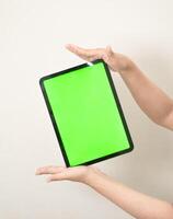 Hand ist halten ein Tab mit Grün Bildschirm auf ein Weiß isoliert Hintergrund foto