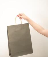 Hand halten ein Einkaufen Papier Tasche gegen ein Weiß isoliert Hintergrund foto
