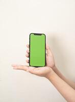 Hand ist halten ein Telefon mit Grün Bildschirm auf ein Weiß isoliert Hintergrund foto