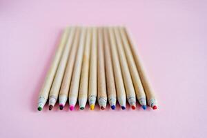 ein einstellen von Bleistifte Lügen auf ein Rosa Hintergrund. zeichnen und erstellen. natürlich Bleistifte gemacht von Holz zum Kinder. hell Farben im das einstellen foto