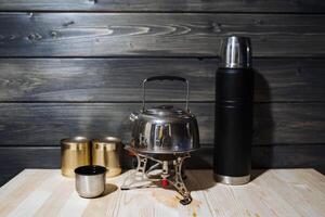 ein einstellen von Camping Utensilien. tragbar Brenner, Wasserkocher, Thermosflasche und Dosen- Lebensmittel. Camping, Essen draußen. Gas Brenner foto