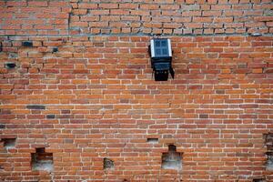 ein groß Scheinwerfer ist montiert auf ein Backstein Mauer. Mauerwerk von das alt Mauer mit Löcher. Straße Beleuchtung, hell Licht beim Nacht. minimalistisch Schuss foto