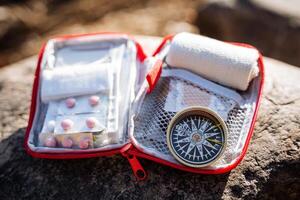 das öffnen Tasche von das zuerst Hilfe Kit Lügen auf ein Stein. Camping Ausrüstung zum Wandern im das Berge. Medikamente zum Notfall, zuerst Hilfe, Kompass zum Orientierung, Tablets. foto