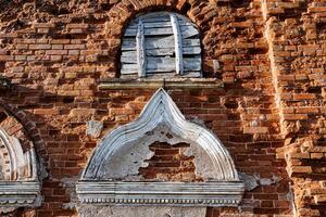 Stuck auf das Fassade von das alt Gebäude, das uralt Struktur von das Haus Aussicht von das Straße, ein schön Muster auf das Mauer von das historisch Haus, ein Fragment von Gips rot Ziegel. foto