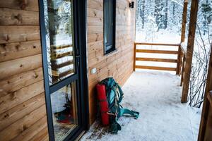 ein Wandern Rucksack mit ein Matte und ein Thermosflasche ist beim das Eingang zu das Haus. ein Ausflug zu das Wald, ein voll einstellen von Wandern Ausrüstung. Winter Reise foto