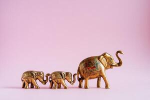 golden Elefant Figuren auf ein Rosa Hintergrund. ein Familie von indisch Elefanten. heilig Tiere im Indien. Glück und Stabilität im das Haus durch Elefanten Energie foto