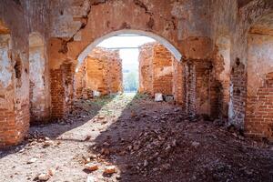 das Innere von das alt ruiniert orthodox Kirche, das Sonne scheint durch das zerstört Fenster im das Wand, das uralt Wände sind rot Ziegel, das Zerstörung von das historisch Monument. foto