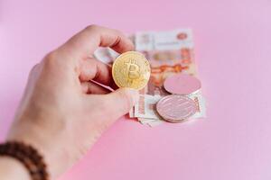 Mann hält ein Bitcoin Münze. modern Währungen und Wege von investieren, Kauf Bitcoin zum ein groß Menge von Geld. austauschen Rubel zum Äther und Bitcoin foto