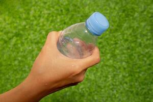 weiblich Hand halten ein Flasche von Wasser oder Mineral Wasser. draussen. foto