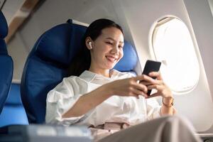 Reisen und Technologie. fliegend beim zuerst Klasse. jung Geschäft Frau Passagier mit Smartphone während Sitzung im Flugzeug Flug foto