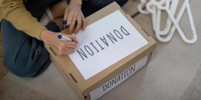 Frau asiatisch vorbereiten ein Lieferung Box mit ihr benutzt Kleidung, Spende und Recycling Konzept foto