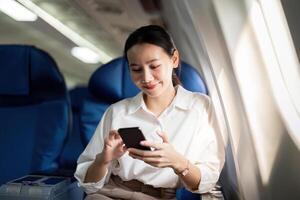 Reisen und Technologie. fliegend beim zuerst Klasse. jung Geschäft Frau Passagier mit Smartphone während Sitzung im Flugzeug Flug foto