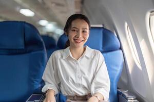 ein Frau ist Sitzung auf ein Blau Flugzeug Sitz mit ein Lächeln auf ihr Gesicht foto