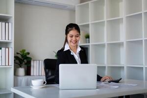 Geschäftsfrau Buchhalter mit Taschenrechner und Laptop zum finanziell Daten Speichern im Büro Zimmer, Geschäft finanziell, Steuer, Buchhaltung Konzept foto