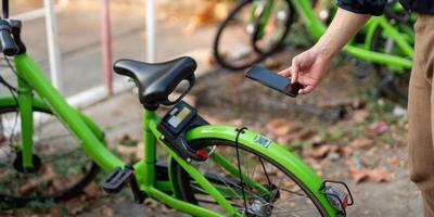 Geschäftsmann mit Handy, Mobiltelefon Anwendung, Scannen qr Code zum Vermietung Fahrrad auf das arbeiten, Öko Transport Konzept foto