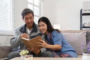 asiatisch Senior Paar lesen Buch Tagebuch zusammen, Sitzung auf gemütlich Sofa im Zuhause Innere. glücklich Pensionierung Aktivität Lebensstil beim Zuhause foto