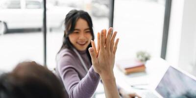 erfolgreich Geschäft Menschen geben jeder andere ein hoch fünf im ein treffen. zwei jung Geschäft feiern Zusammenarbeit im ein Büro foto