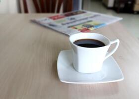 Kaffee Tasse und Zeitung auf das hölzern Tisch. foto