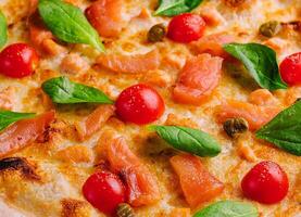 lecker Meeresfrüchte Pizza mit Tomaten, Käse, Lachs und Basilikum foto